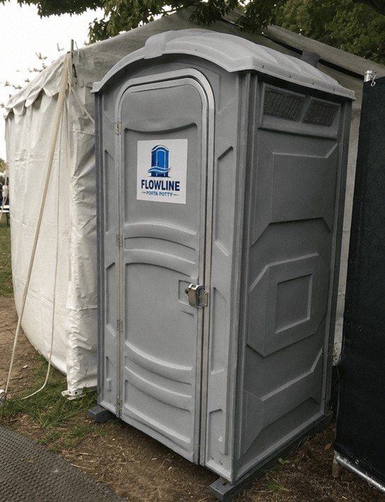 Grey deluxe flushing porta potty unit next to an event tent