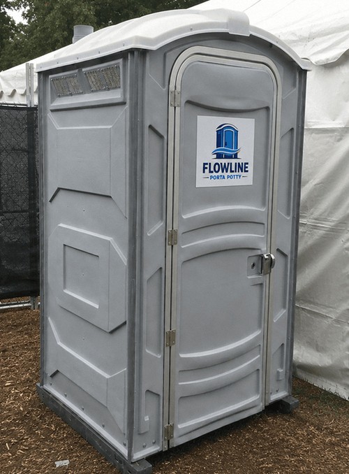 Portable restroom staged behind a marquee tent at an outdoor event